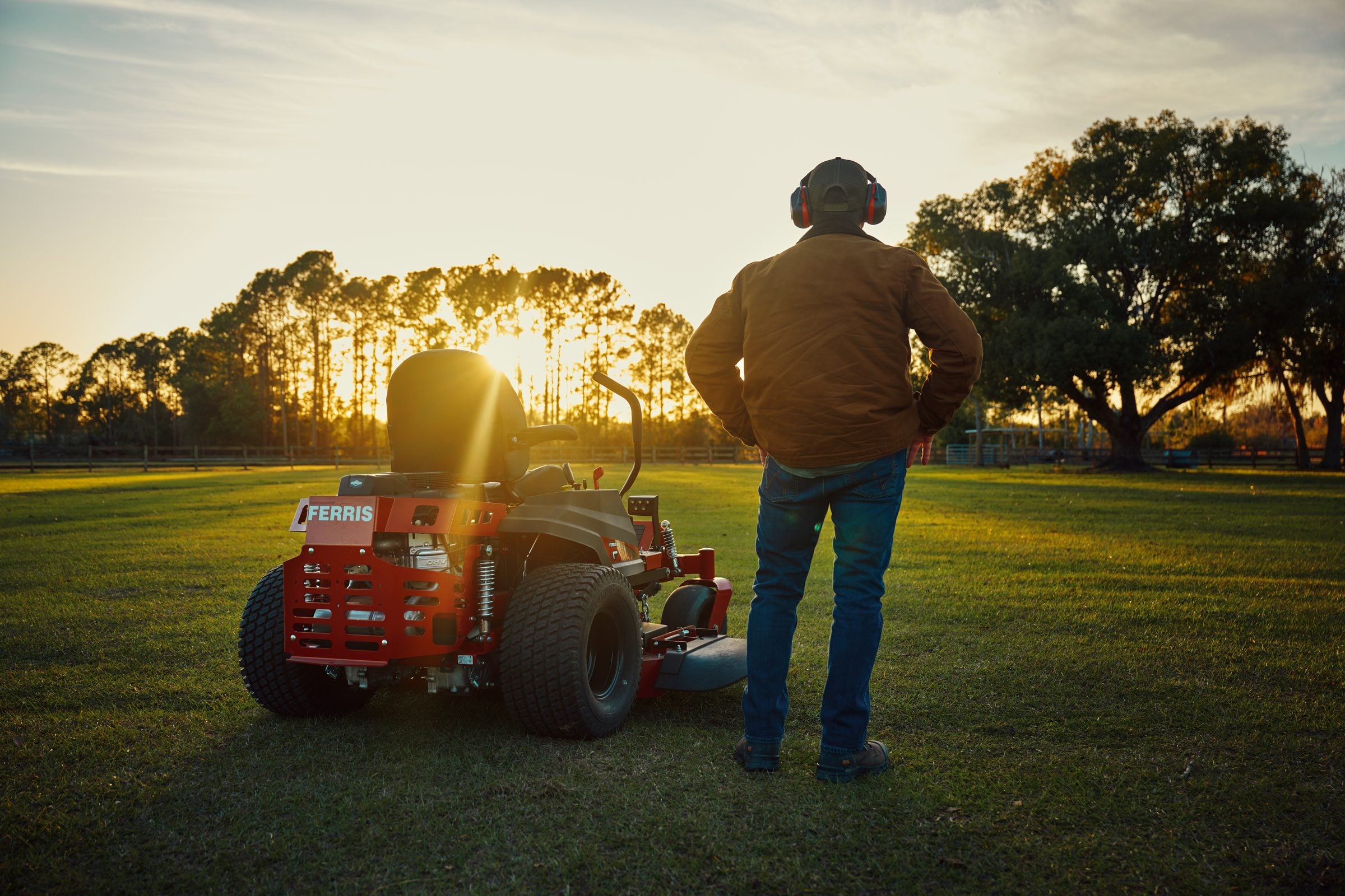 A Ferris zero-turn mower working an open property in late afternoon light